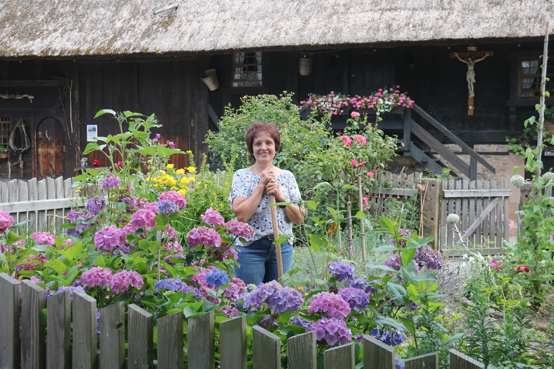 Martha Bohnert zwischen blühenden Hortensien im Bauerngarten vor dem Hof